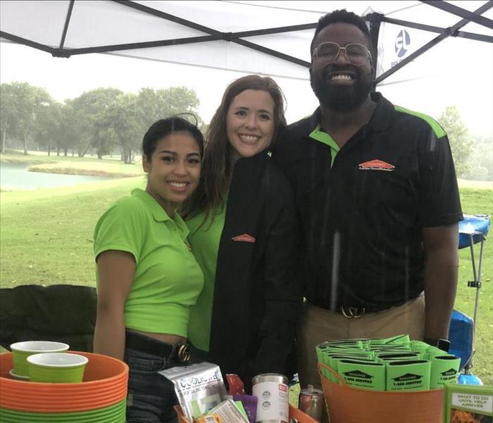 2 members of the marketing team with owner Alison Zelaya smiling under their tent at a Golf Tournament.