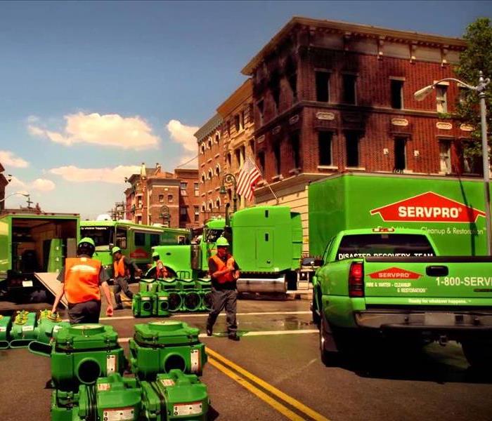 Multiple SERVPRO vehicles and equipment in the middle of a city doing storm clean up.
